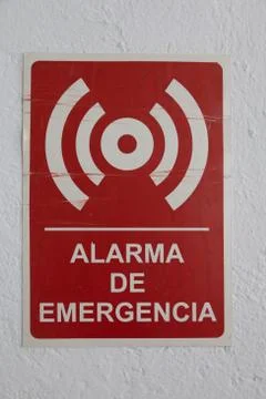 A red alarma de emergencia - emergency alarm - sign on the white wall under t Stock Photos