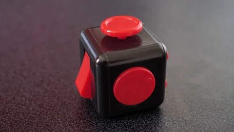 Red and black fidget cube on black table top, focus pull Stock Footage 77918456