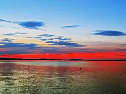 Red and blue cloudy sunset sky over the lake, southern Urals Stock Photos