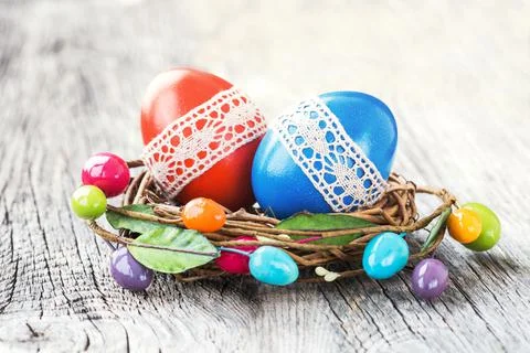Red and blue Easter eggs decorated with lace in small decorative nest. Selective Stock Photos