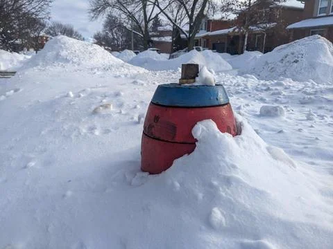 Red and Blue Fire Hydrant Buried Deep in Large Snow Banks on Suburban Street Foto stock