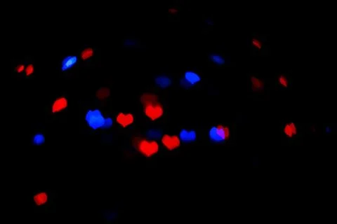 Red and blue lights in the shape of the hearts on the black background. Stock Photos