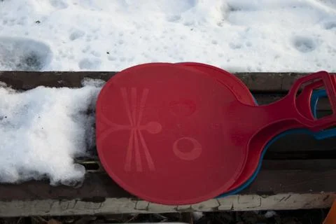 Red and blue plastic beach toys on a bench in the snow. Stock Photos