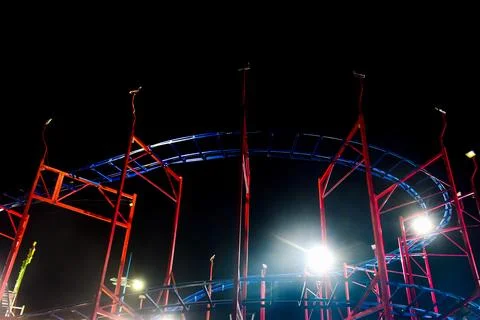 Red and Blue roller coaster under a dark sky Stockfoto's