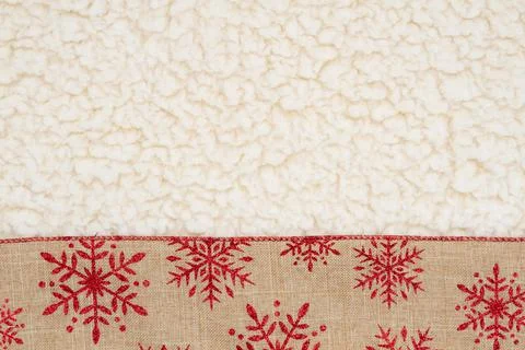 Red and brown snowflake border winter background on beige sherpa material Foto stock