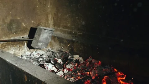 The red and dark gray coals inside the brazier are mixed with a metal scoop Stock Footage 112061408