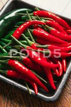 Red And Green Chili Peppers Close Up On Wooden Background