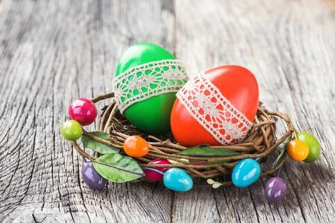 Red and green Easter eggs decorated with lace in small decorative nest Stock Photos