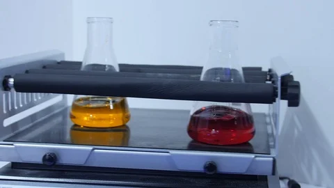 Red and orange liquid is mixed by a machine in a laboratory 動画素材 126715820