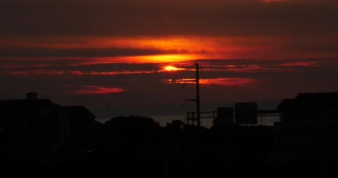 Red and orange sunset at the beach over the sound silhouette of houses Video stock 205450736