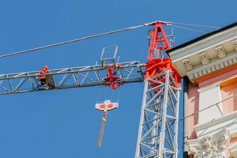 Red and silver construction crane towering next to historic building with c.. Stock Photos