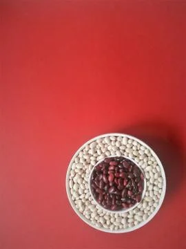 Red and white bean wick in a saucer on a red. top view. Flatley. Stock Photos