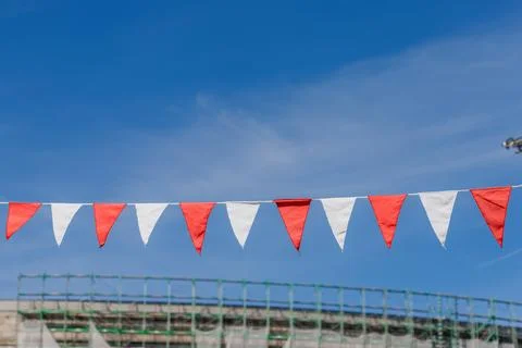 Red and white bunting flags hanging under blue sky Stock Photos