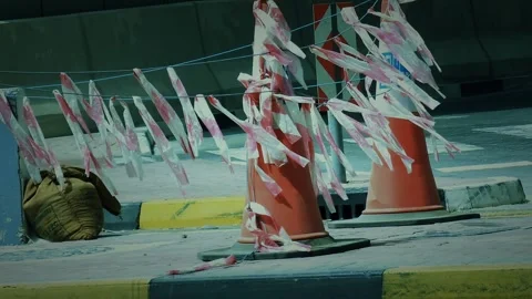 Red and white caution tape streams from traffic cones on a windy 스톡 동영상 314957968