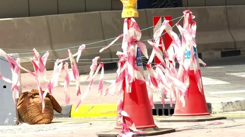 Red and white caution tape streams from traffic cones on a windy day Stock Footage 314957976