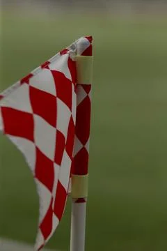 Red and white checkered corner flag on a grassy sports field Stock Photos