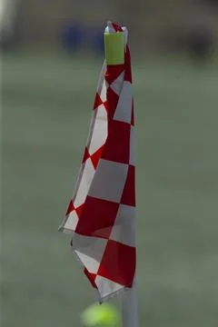 Red and white checkered corner flag on sports field Stock Photos