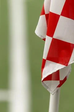 Red and white checkered corner flag on green football pitch Stock Photos