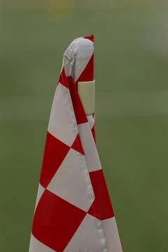 Red and white checkered corner flag on grassy field Stock Photos