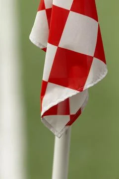 Red and white checkered corner flag on green background Stock Photos