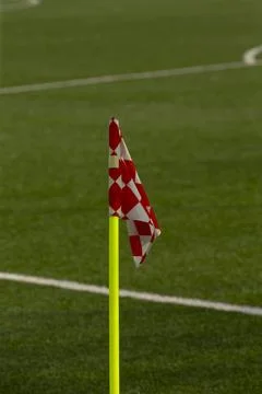 Red and white checkered corner flag on green soccer pitch Stock Photos