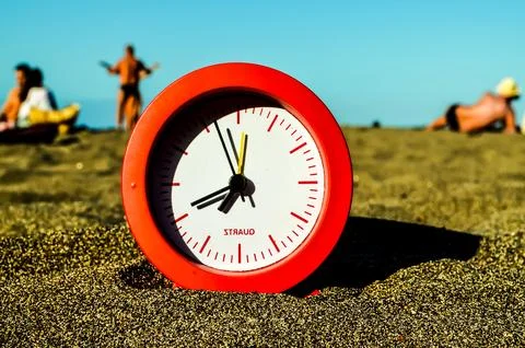 A red and white clock is sitting on the sand Foto stock