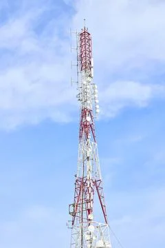 Red and white communication tower with antennas and dishes Stock Photos
