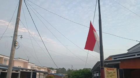The red and white flag flies between power poles and wires in the afternoon Stock Footage 243739928