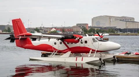 Red and white floatplane next to a pier Stock Photos