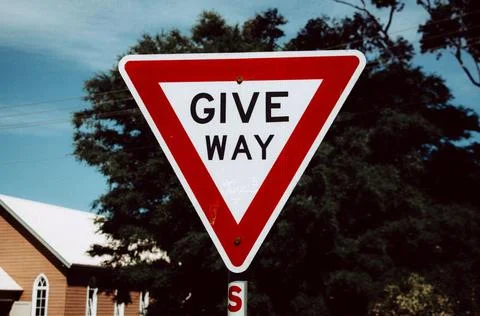 Red And White Give Way Traffic Sign Against A Clear Blue Sky Foto stock