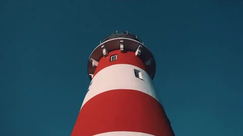 Red and white lighthouse against a clear blue sky. Bottom view. Close-up. Stock Footage 147405412