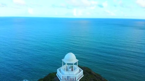 A red and white lighthouse is on a hill overlooking a town Видео 294042800