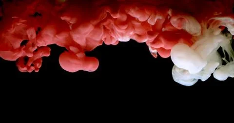 Red and white paint cloud spraying in water on black background. Stock Photos