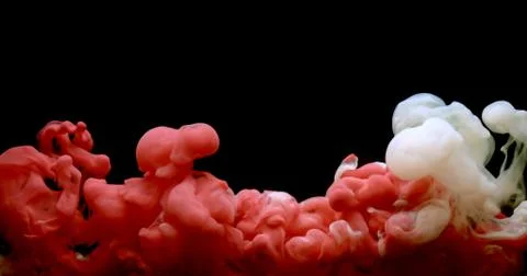 Red and white paint cloud spraying in water on black background. Stock Photos