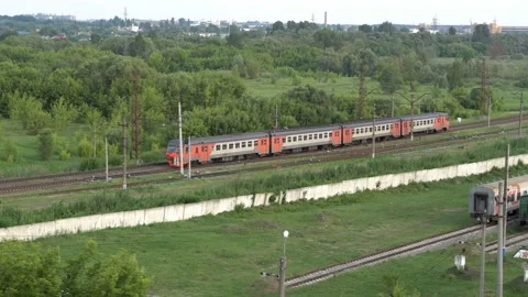 A red and white passenger train of several cars rides on a railway in a rural Stock Footage 143148649
