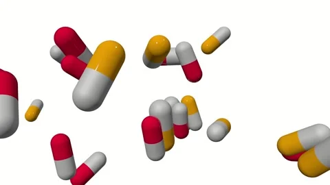 Red and White pill capsules being dropped and moved along a table Stock Footage 243547982