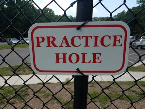 Red and white practice hole sign on metal fencing Stock Photos