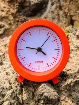A red and white Quartz clock sits on a rock Foto stock