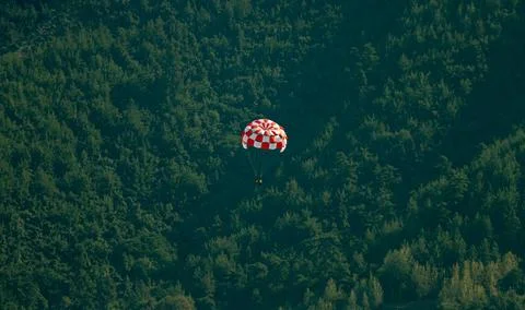 Red and white square-designed air balloon flying over the forest full of thick, Fotos Stock
