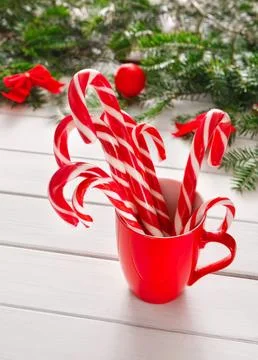 Red and white striped candy canes in a red mug on table Stock Photos