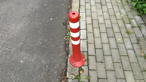 Red and white striped flexible bollard on curb between asphalt road  Vídeos de archivo 344041724