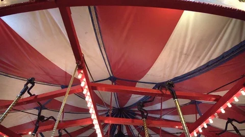 Red and white striped underside of carousel ride turning in slow motion Stock Footage 124668498