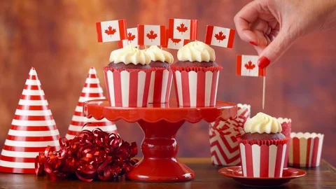 Red and white theme cupcakes with Canadian maple leaf flags for first of July Stock Footage 90022293
