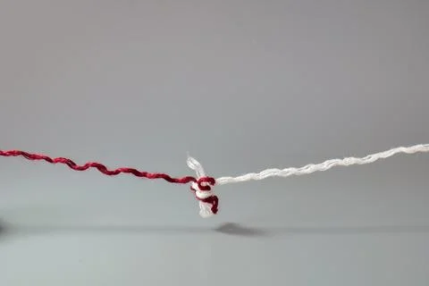 Red and White Threads Tied Together with a Knot Stock Photos