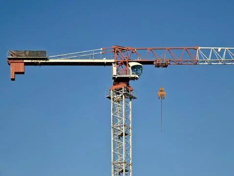 Red and white tower crane jib with suspended hook and operator cabin agains.. Stock Photos