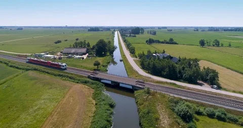 Red and White Train Crossing Bridge, Friesland, The Netherlands – 4K Drone Stock Footage 120829444