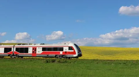 Red and white train moves through green field Stockfoto's