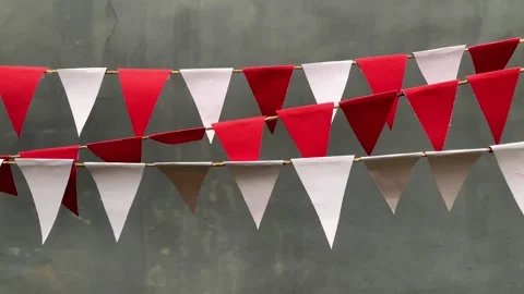 Red and white triangular bunting flags hang against a gray background Stock Footage 312499582