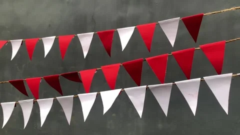 Red and white triangular bunting flags hang against a gray background Stock Footage 312499656