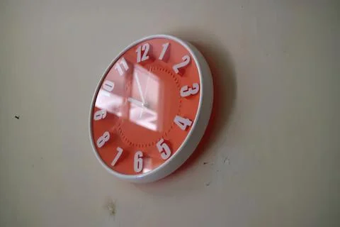 Red and white wall clock showing time on a beige wall Stock Photos